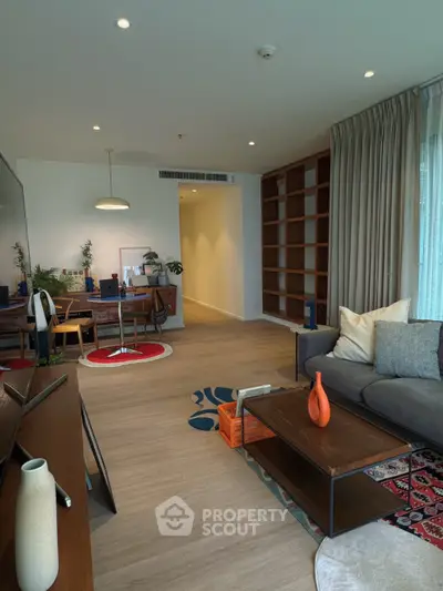 Spacious modern living room with stylish decor and open layout, featuring a cozy seating area and elegant shelving.