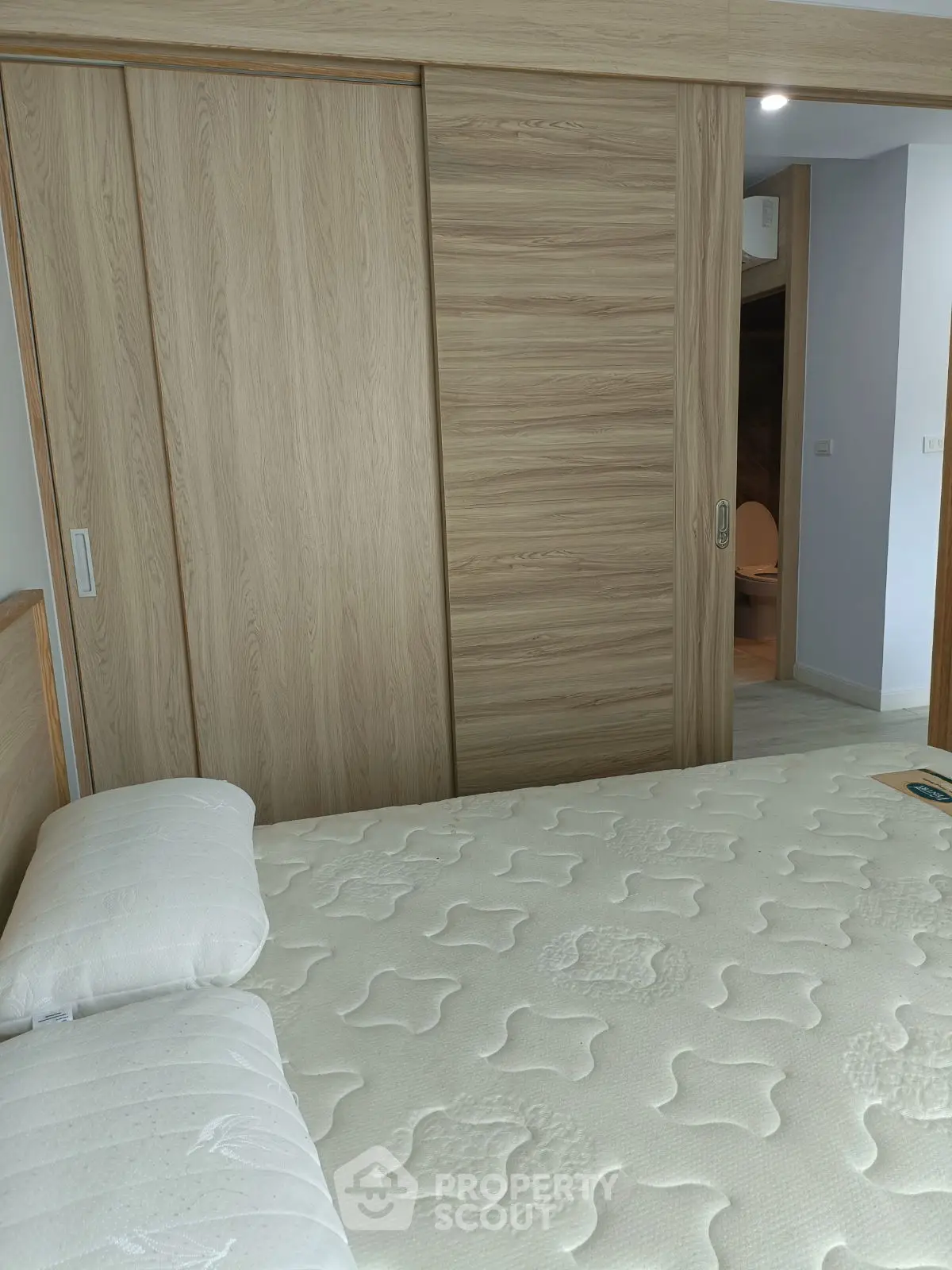 Modern bedroom with wooden sliding closet doors and comfortable mattress