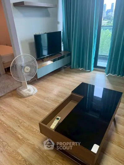 Modern living room with TV, fan, and glass coffee table overlooking city view.