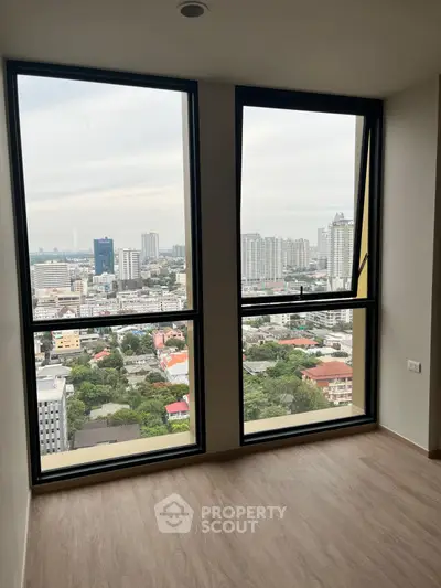 Stunning city view from high-rise apartment with large windows and wooden flooring.