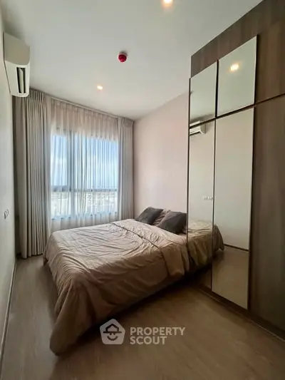 Modern bedroom with large window and mirrored wardrobe in a stylish apartment.