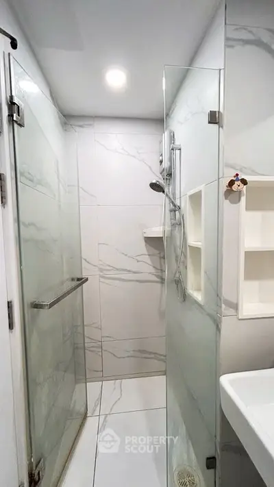 Modern bathroom with glass shower enclosure and marble-style tiles