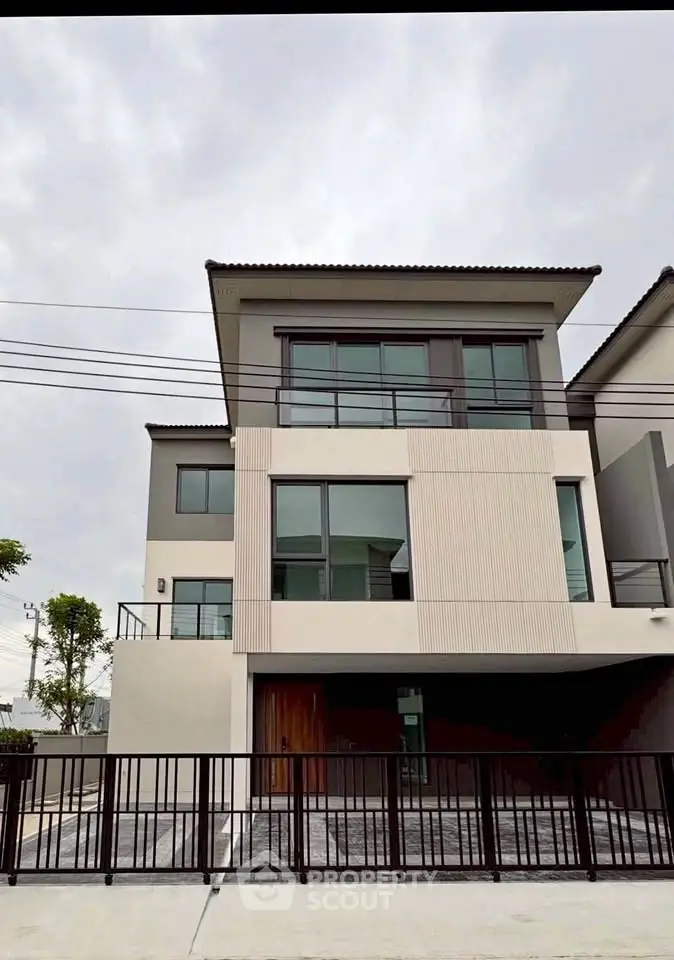 Modern three-story house with sleek design and large windows in a suburban neighborhood.