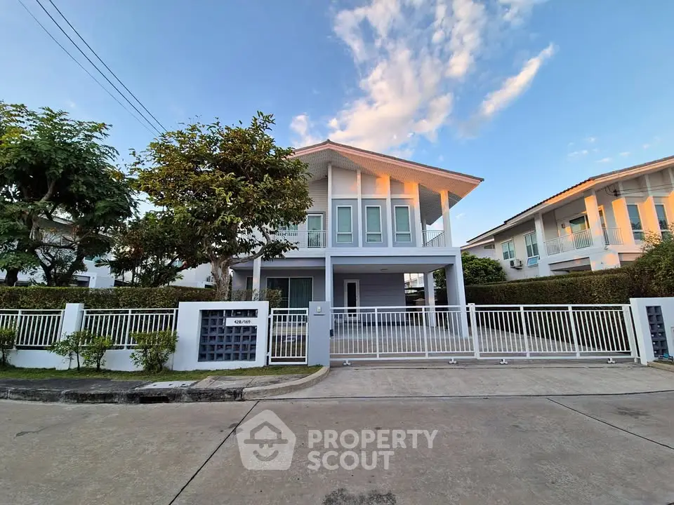 Modern two-story house with spacious driveway and lush greenery in a serene neighborhood.