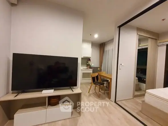 Modern open-plan living room with TV and dining area in stylish apartment.