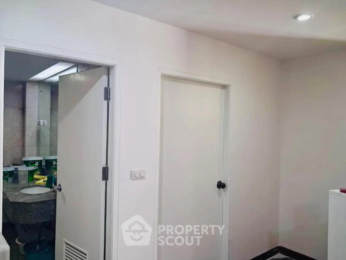 Interior view of a simple hallway with doors leading to a bathroom and another room.