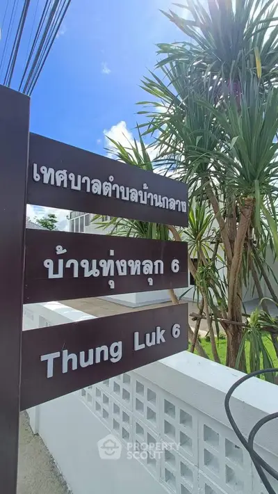 Charming residential area sign with lush greenery and clear blue sky.