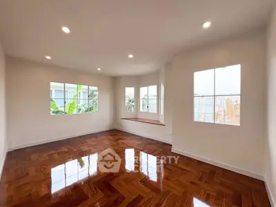 Spacious living room with polished wooden floors and large windows offering natural light.
