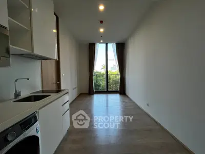 Modern apartment with open kitchen and balcony view, featuring sleek design and natural light.
