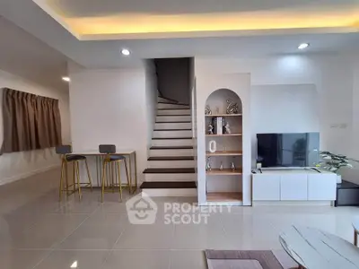Modern living room with sleek staircase and stylish decor in a contemporary home.