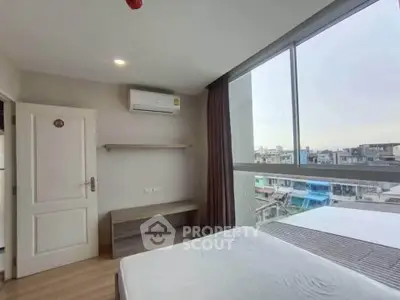 Modern bedroom with large windows offering city views and minimalist decor.