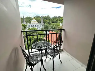 Charming balcony with elegant wrought iron furniture and scenic view of lush greenery and unique architecture.