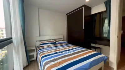 Cozy bedroom with striped bedding and large window offering natural light