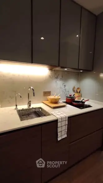 Modern kitchen with sleek cabinetry and under-cabinet lighting, featuring a stylish sink and countertop accessories.