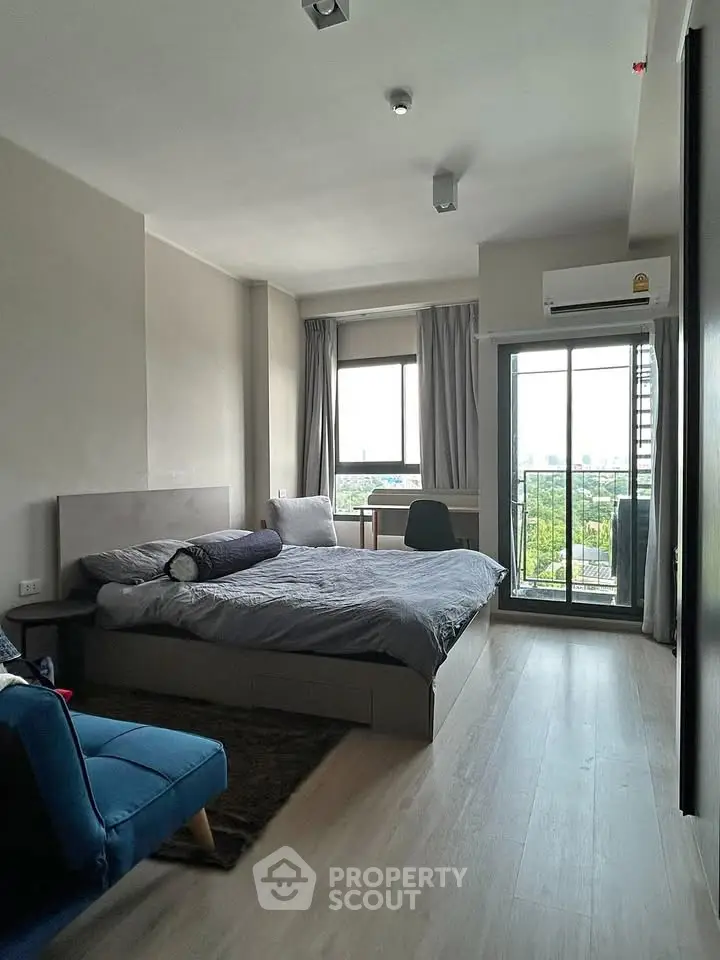 Modern bedroom with balcony and city view, featuring stylish decor and natural light.
