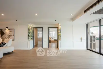 Spacious modern living room with elegant decor and large windows offering city views.