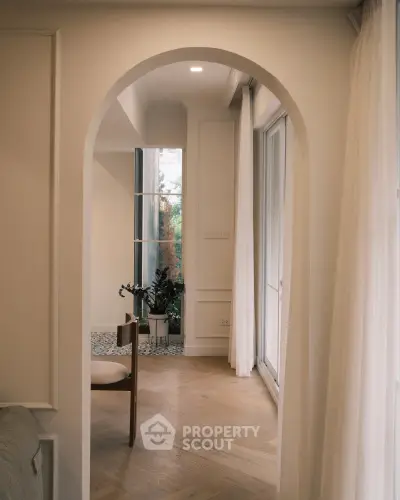 Elegant interior with arched doorway, wooden flooring, and natural light, perfect for modern living.