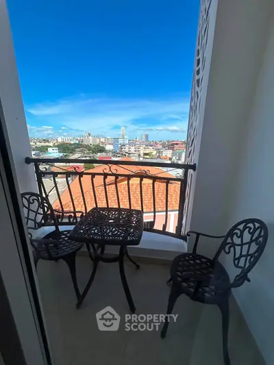 Charming balcony with city view, featuring elegant wrought iron furniture, perfect for relaxation.