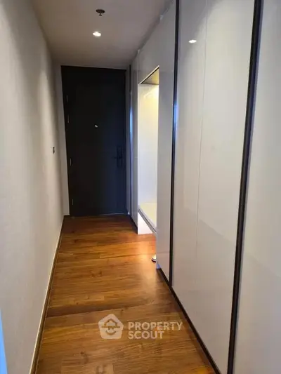 Sleek modern hallway with wooden flooring and built-in storage