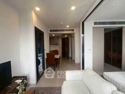 Modern apartment interior with open living and dining area, featuring sleek furniture and a compact kitchen.