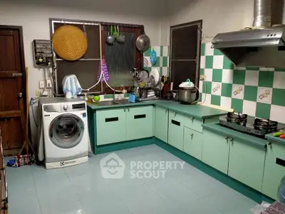 Charming kitchen with vintage green cabinets and modern appliances, featuring a washing machine and gas stove.