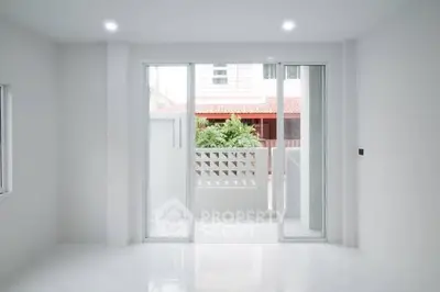 Bright minimalist room with large sliding glass doors leading to a balcony.