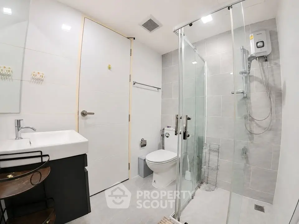 Modern bathroom with glass shower and sleek fixtures in contemporary apartment.