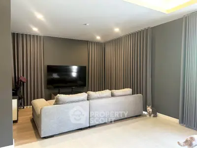 Modern living room with sleek gray sofa and large TV, perfect for relaxation.