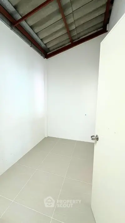 Minimalist small room with white walls and tiled floor, perfect for storage or a compact office space.