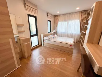 Modern bedroom with wooden flooring, large windows, and stylish furniture.