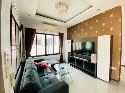 Modern living room with stylish decor, large TV, and comfortable seating in a well-lit space.