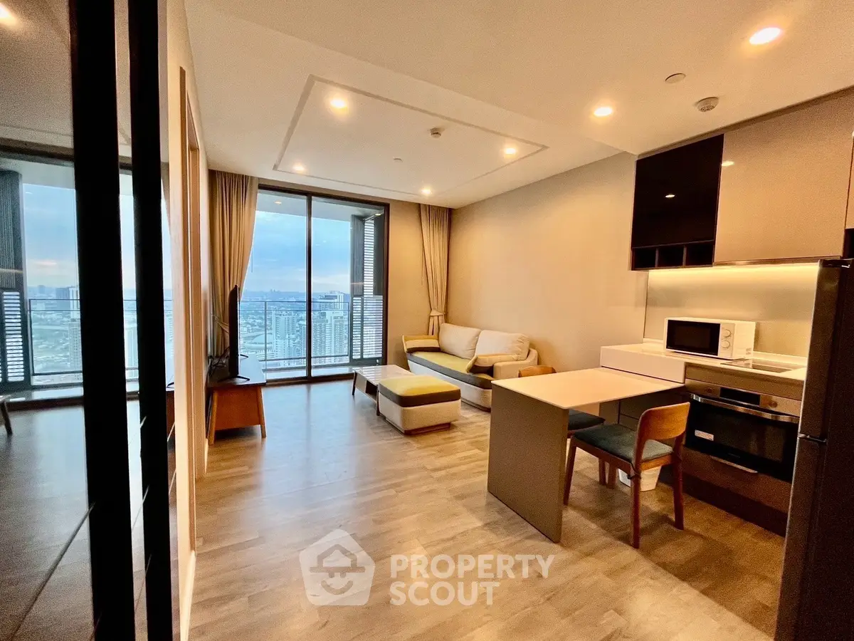 Modern open-layout living room with kitchen, featuring large windows and city view.