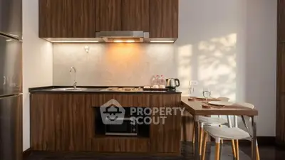 Modern kitchen with wooden cabinets, built-in microwave, and dining area in cozy apartment.