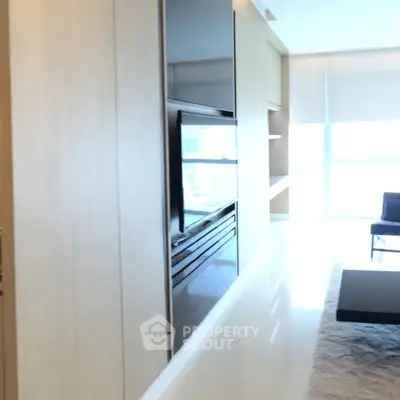 Modern living room with sleek built-in cabinetry and large window for natural light.