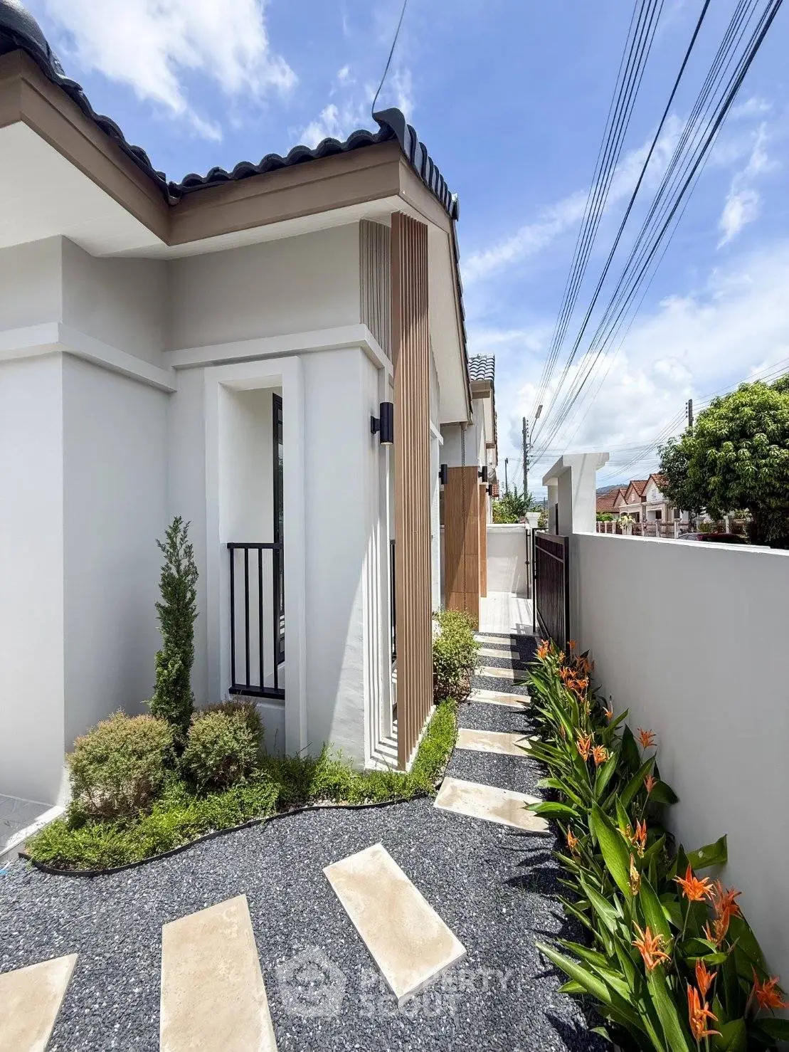 Modern house exterior with landscaped garden and pathway under a clear blue sky.