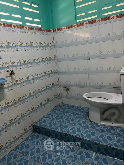 Charming bathroom with unique tile design and elevated toilet area, perfect for a cozy home.