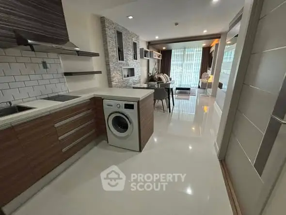 Modern open-layout kitchen with integrated washing machine and stylish living area.