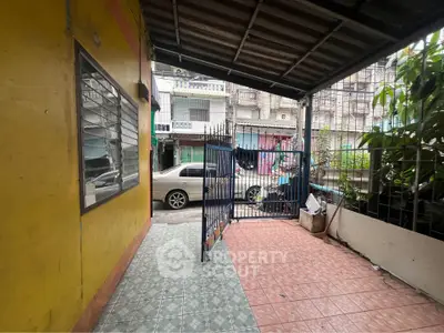 Charming urban home with gated entrance and vibrant yellow exterior, perfect for city living.