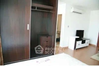 Modern bedroom with sleek wardrobe and entertainment unit, featuring air conditioning for comfort.