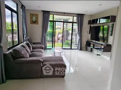 Spacious living room with modern decor and large windows overlooking garden