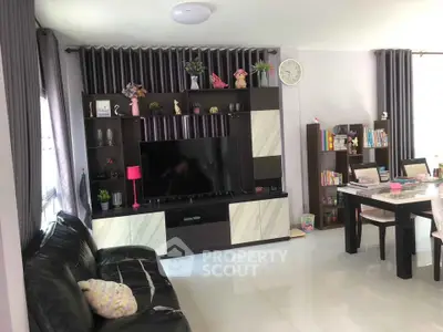 Modern living room with sleek entertainment center and dining area, perfect for family gatherings.