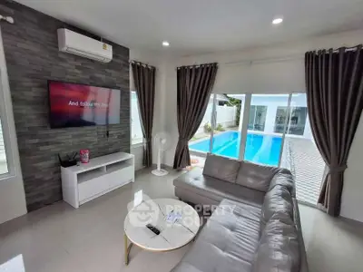 Modern living room with pool view, sleek furniture, and large windows.