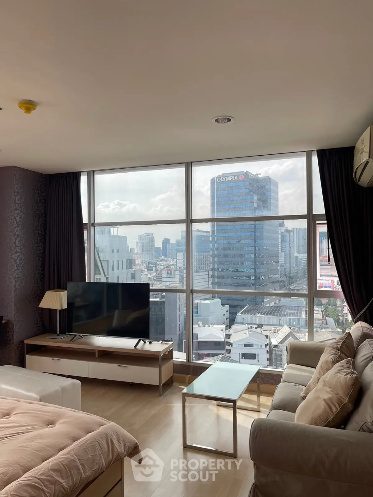 Spacious living room with stunning city view and modern furnishings in high-rise apartment.