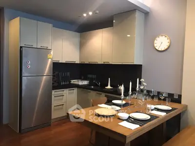 Modern kitchen with dining area, featuring sleek cabinetry and stainless steel appliances.