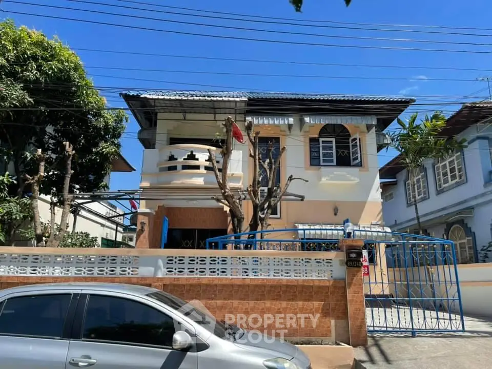 Charming two-story house with gated entrance and balcony in a sunny neighborhood.