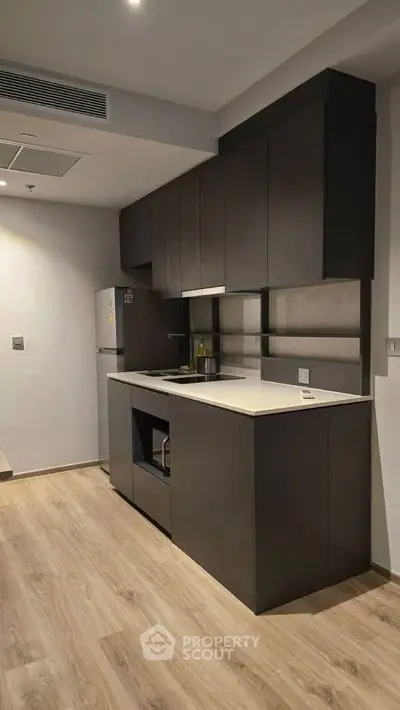 Modern kitchen with sleek cabinetry and built-in appliances, featuring a minimalist design and wooden flooring.
