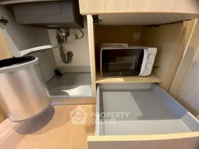 Modern kitchen cabinet with built-in microwave and pull-out trash bin