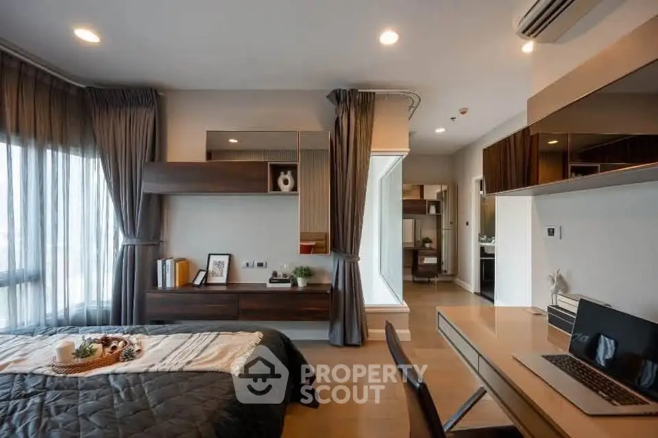 Modern bedroom with stylish decor and workspace, featuring large windows and elegant furnishings.