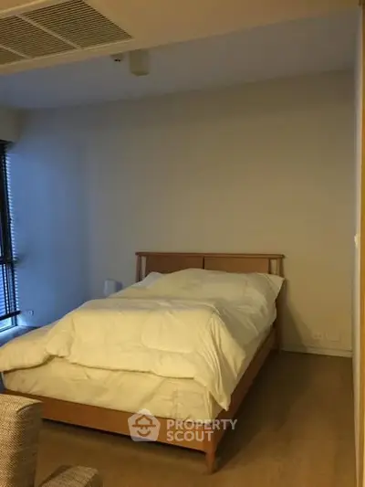 Cozy bedroom with wooden bed frame and soft lighting, perfect for relaxation.