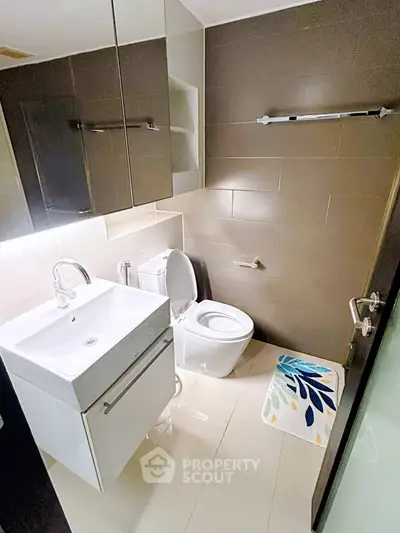 Modern bathroom with sleek fixtures and stylish design, featuring a white vanity and contemporary toilet.